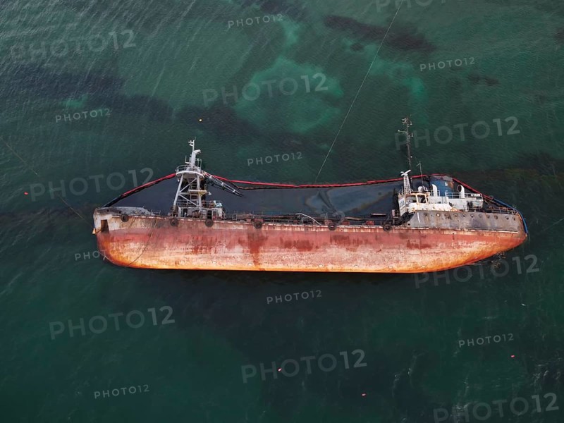 Top view of an old tanker that ran aground, overturned and polluted the coast with oil spilled from it. Ecological catastrophe