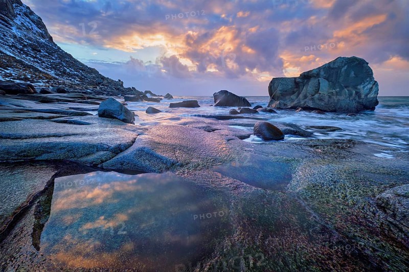 Rocks on beach of fjord of Norwegian sea in winter on sunset. Utakliev beach, Lofoten islands, Norway, Europe