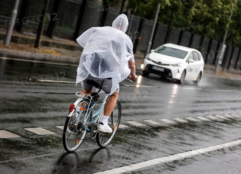 Bicycle rider with rain cape in heavy rain, Berlin, 23.06.2023