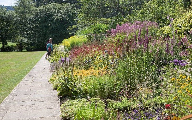 People enjoying summer flower borders in the botanical gardens at Bath, north east Somerset, England, United Kingdom, Europe