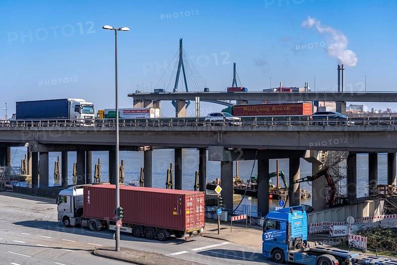 The Köhlbrand Bridge in the Port of Hamburg, rear, front trucks on the Waltershoferdam, access to the HHLA Container Terminal Burchardkai, middle traffic on the A7 motorway, spans the 325 m wide Köhlbrand, an arm of the Süderelbe, the bridge is over 3600 metres long, 53 metres above the water, piers 135 m high, more than 30, 000 vehicles use the B3 bridge daily, important connection to the port, it is dilapidated, is to be rebuilt, Hamburg, Germany, Europe