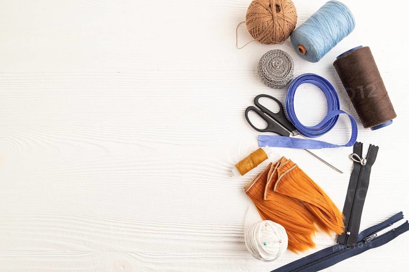 Sewing accessories: scissors, thread, thimbles, braid on white wooden background. Top view, flat lay, copy space