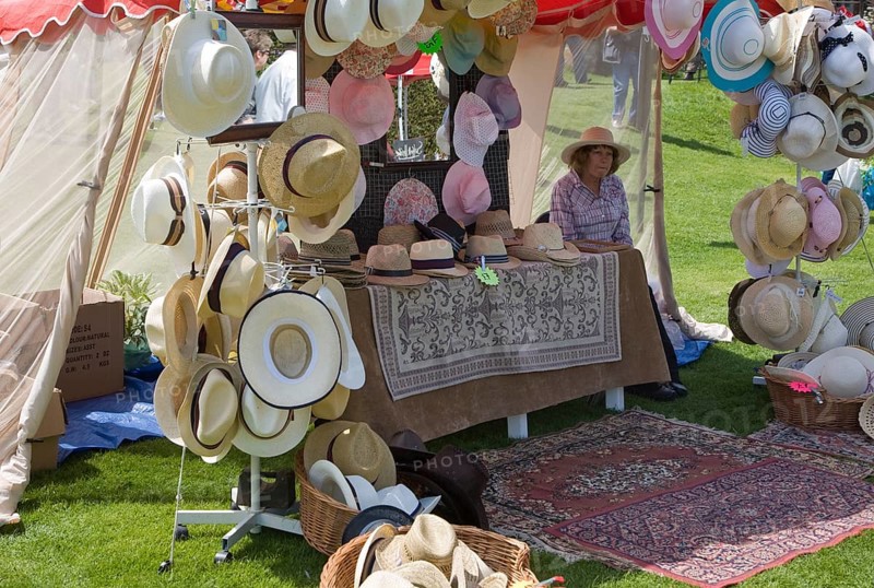 Woman selling hats from tent stall during garden event at Helmingham Hall, Suffolk, England, United Kingdom, Europe