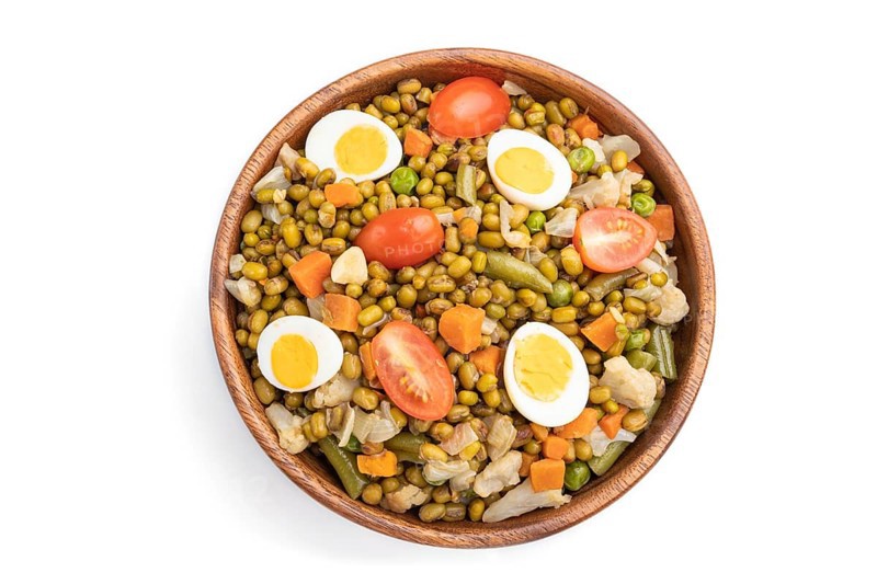 Mung bean porridge with quail eggs, tomatoes and vegetables isolated on white background. Top view, flat lay
