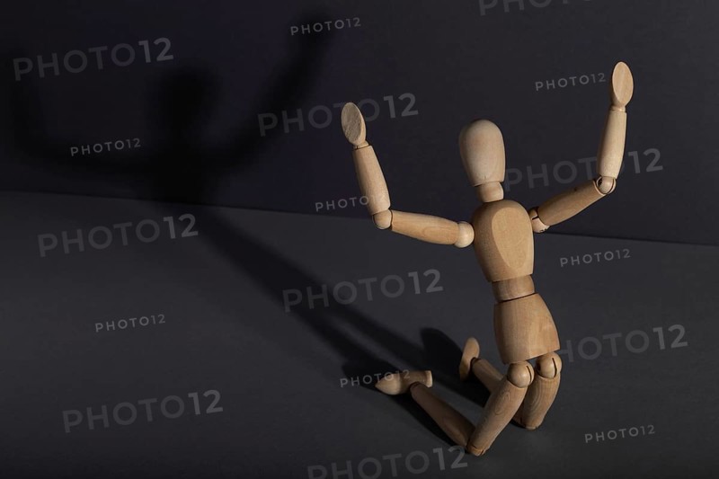 Wooden mannequin in imploration, praying position on gray background. religion, despair concept. copy space, hard light