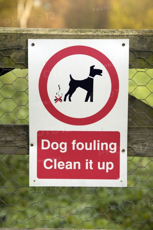 Sign saying Dog fouling Clean it up on fence, UK