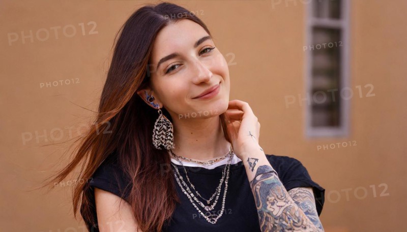 Smiling young woman with dark hair and visible tattoos poses relaxed, AI generated, AI generated
