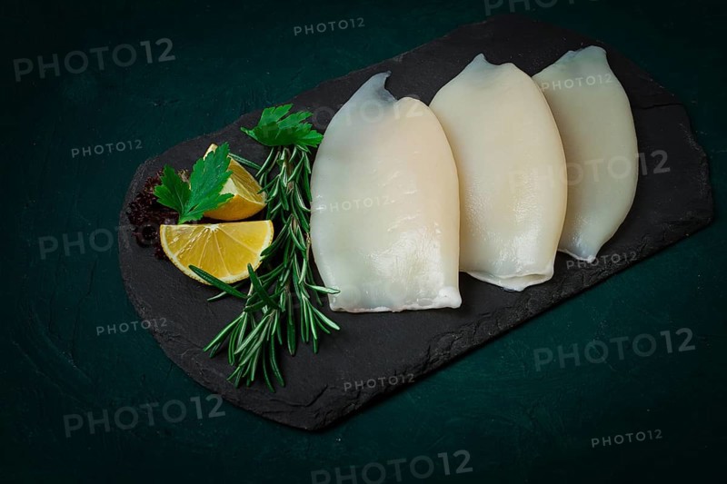 Fresh squid body, raw, three carcasses, top view, on black slate, no people