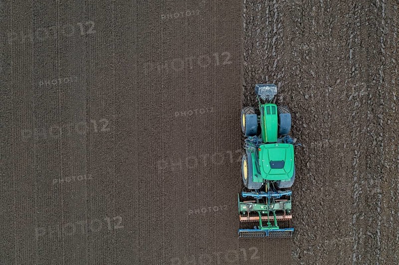 Early potatoes are laid in the soil of the field with a planting machine, tractor with roundabout harrow prepares the soil, agriculture, spring