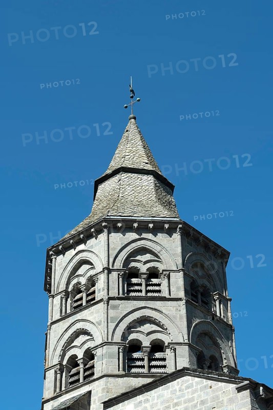 Orcival. Bell tower of the Notre-Dame d'Orcival basilica showcasing Romanesque architecture under a clear blue sky, Puy de Dome, Auvergne-Rhone-Alpes, France, Europe