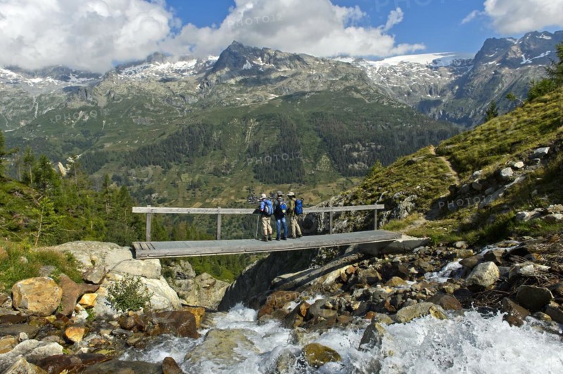 Hikers cross a narrow bridge over the Nästbach torrent on the way to the Bietschhorn hut, near Blatten, Lötschental, Valais, Switzerland, Europe