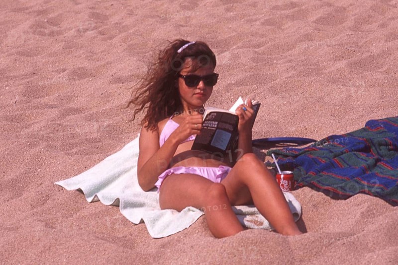 Young woman sunbathing on the beach and reading a book in Calella, Costa Brava, Barselona, ??Catalonia, Spain, Southern Europe. Scanned thumbnail slide, vintage, retro, funny, Europe