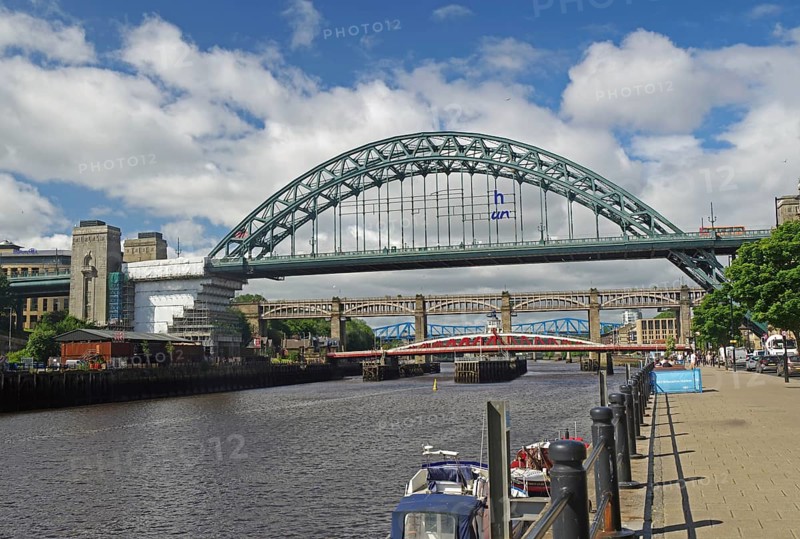 Several bridges over a river in a city, flanked by buildings and boats on a sunny day under a blue sky with clouds, Newcastle, Northern England, United Kingdom, Europe
