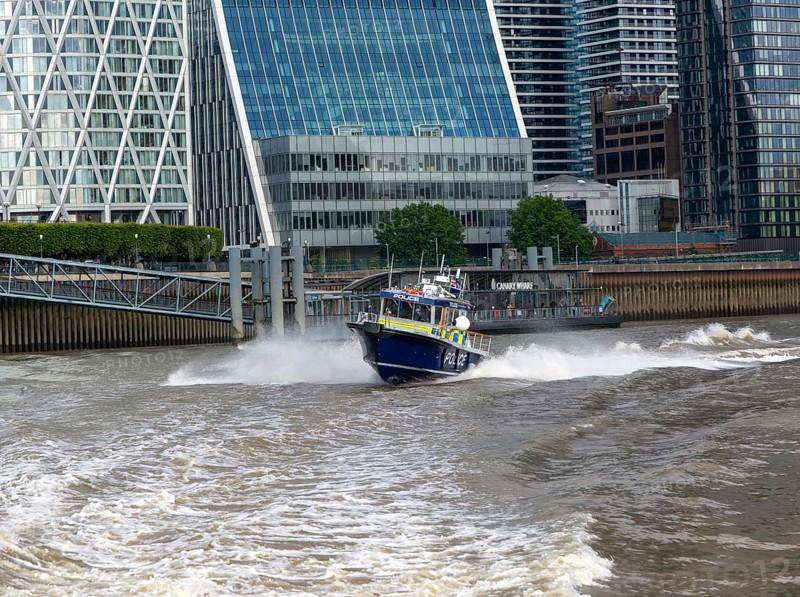 Metropolitan police speedboat motor launch travelling at high speed, Canary Wharf, River Thames, London, England, UK
