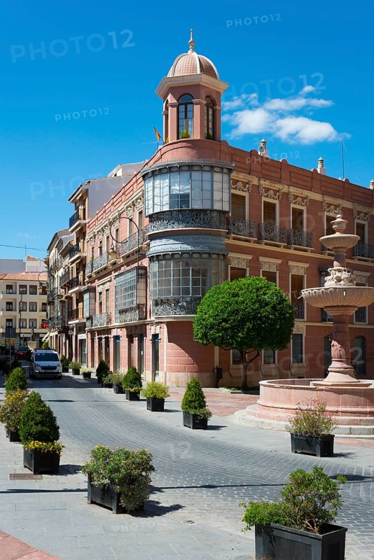 Historic building with bay window on an urban street with fountain and trees under a blue sky, Casa Bouderé, House Boudere, Antequera, Malaga, Andalusia, Spain, Europe