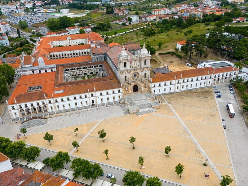 An aerial view of a historic monastery with red roofs in a town with surrounding landscape, Aerial view, Mosteiro de Alcobaça Monastery, Alcobaca, Oeste, Centro, Portugal, Europe