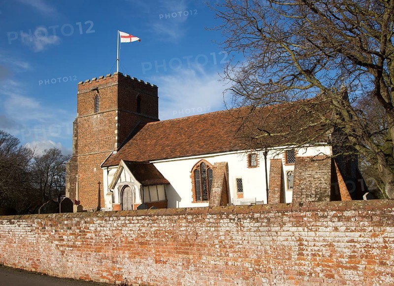 Red cross of flag of St George flying from tower of village Saint Peter church, Levington, Suffolk, England, UK