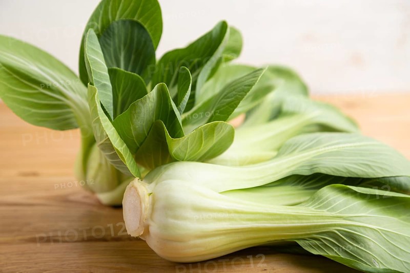 Fresh green bok choy or pac choi chinese cabbage on a brown wooden background. Side view, close up, selective focus