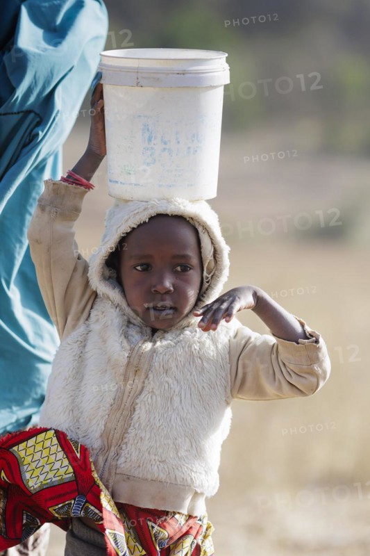 Little girl carrying a heavy bucket of water on her head, Maraban Dare, 07/02/2024