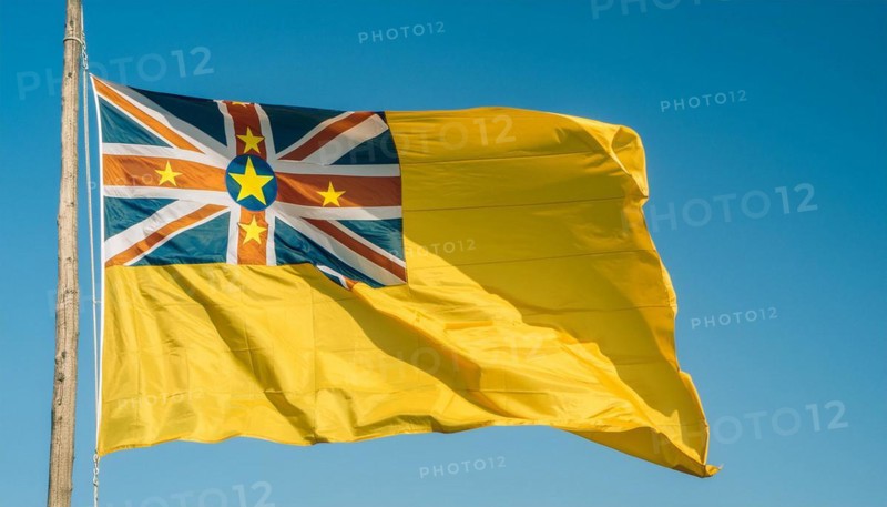 The flag of Niue, an island state in the Pacific Ocean, flutters in the wind, isolated against a blue sky