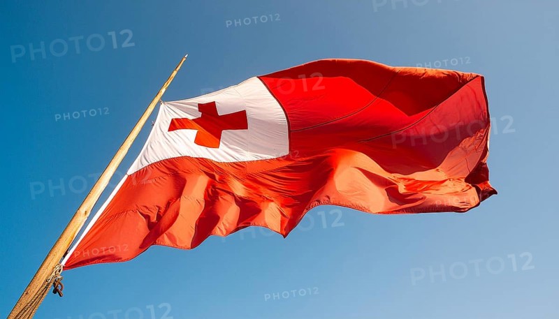 The flag of Tonga, Pacific island state, flutters in the wind, isolated against a blue sky