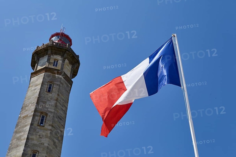 Spire of the Phare des Baleines and a waving French flag in Saint-Clément-des-Baleines, Département Charente-Maritime, Nouvelle-Aquitaine, France, Europe