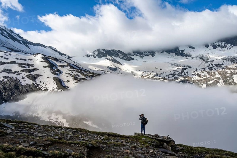 Mountaineer photographed, in front of mountain landscape, high fog in the valley, glaciated mountains with Schlegeiskees, Berliner Höhenweg, Zillertal Alps, Tyrol, Austria, Europe