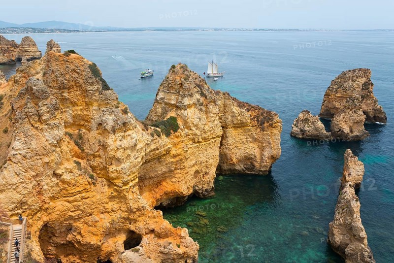 Rugged cliffs and rocks rise from the crystal clear water near sailing boats, Ponta da Piedade, point of mercy, Lagos, Algarve, Portugal, Europe