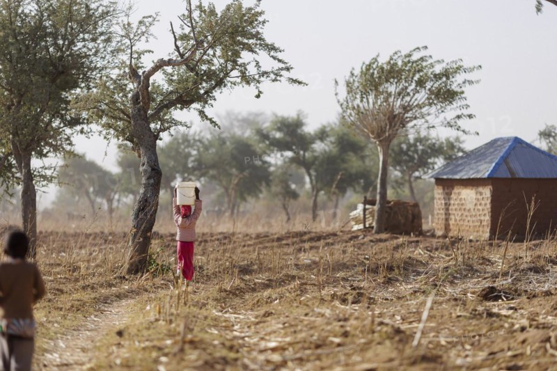 Girl carrying a heavy bucket of water on her head, Maraban Dare, 07/02/2024