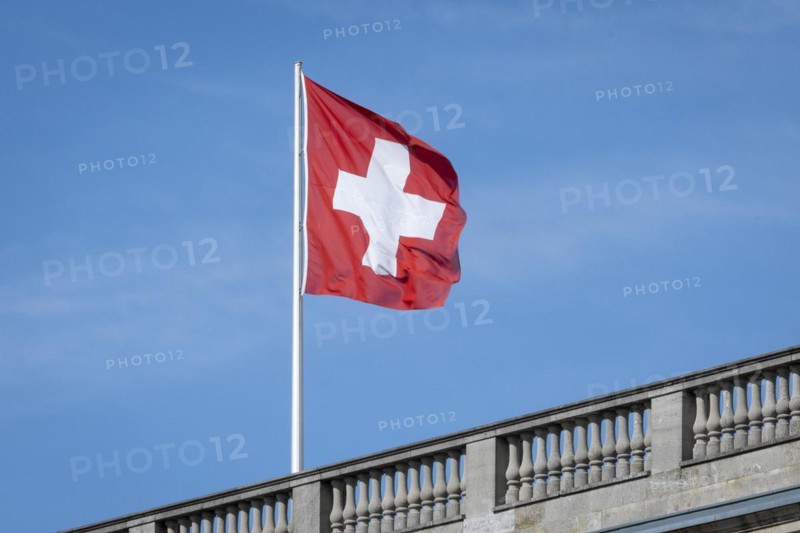 The Swiss flag flies against a blue sky on the roof of the Swiss Embassy in Berlin, 28 March 2024