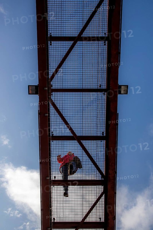 Lattice walkway, people walk over a walkway at a height of a good 15 metres, made of steel lattice, seen from below, viewing platform