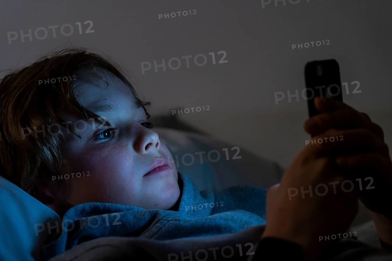 A boy plays computer games on a mobile phone, smartphone