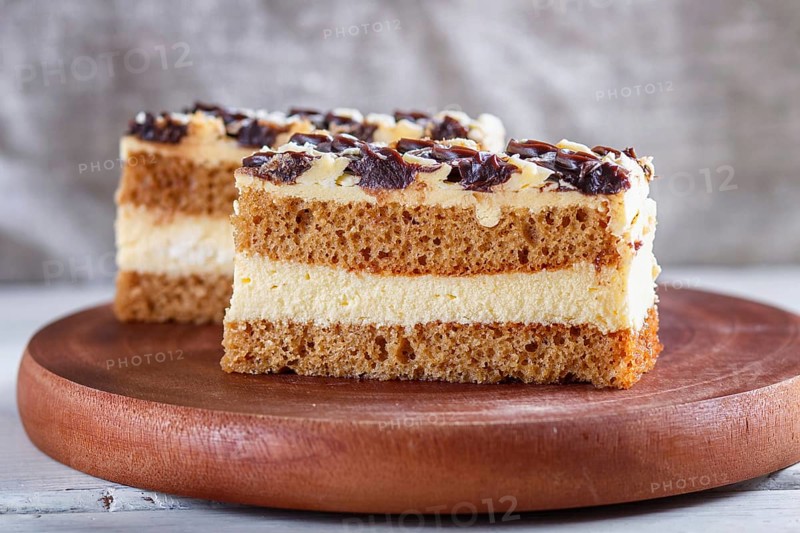 A piece of cake with milk and butter cream on a wooden kitchen board, close up, selective focus, white background