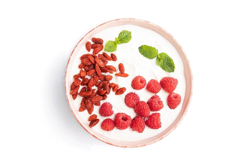 Yogurt with raspberry and goji berries in ceramic bowl isolated on white background. top view, flat lay, close up