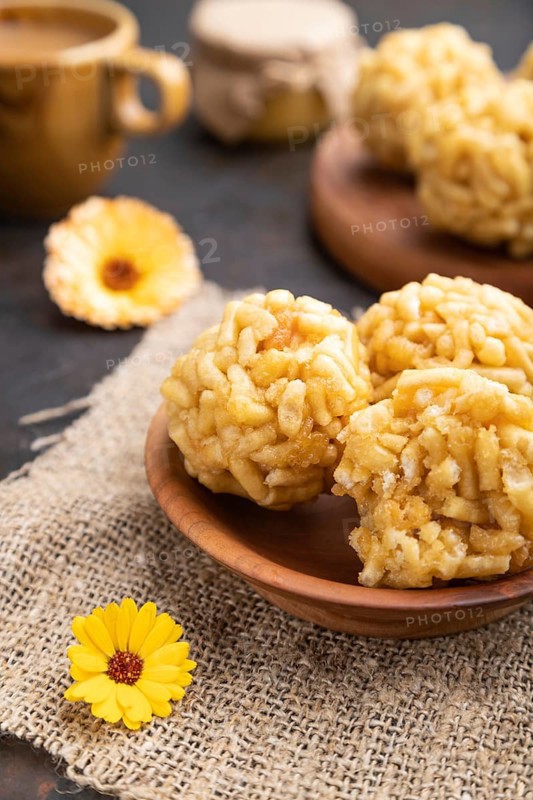 Traditional Tatar candy chak-chak made of dough and honey with cup of coffee on a black concrete background and linen textile. Side view, close up, selective focus