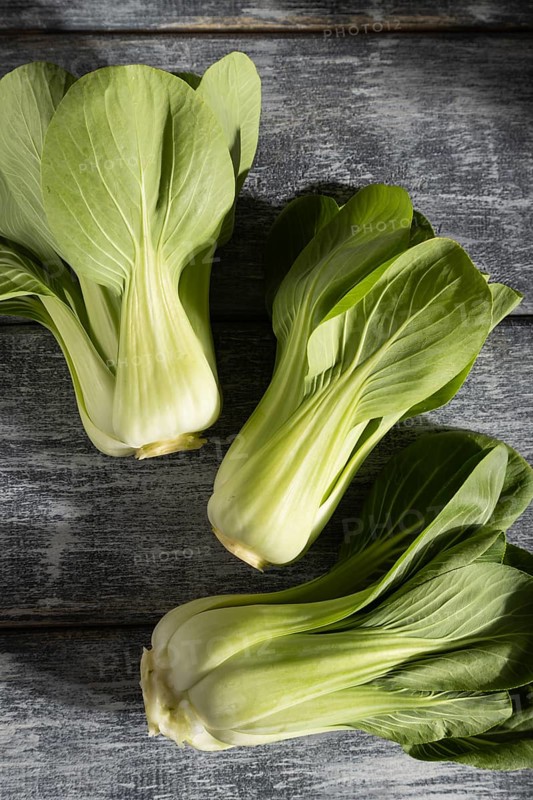 Fresh green bok choy or pac choi chinese cabbage on a gray wooden background. Hard light, contrast. Top view, close up, flat lay