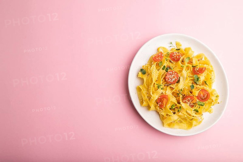 Reginelle semolina pasta with tomato, eggs, sesame and microgreen sprouts on a pastel pink background. Top view, flat lay, copy space