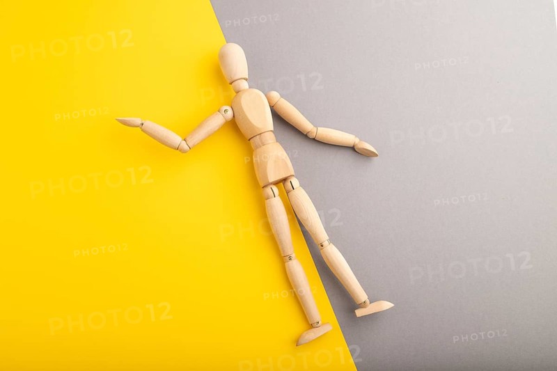 Wooden mannequin lies on gray and yellow pastel background. copy space, isolated, presentation concept, trendy colors