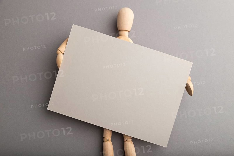 Wooden mannequin holding gray blank poster on gray pastel background. copy space, isolated, presentation concept