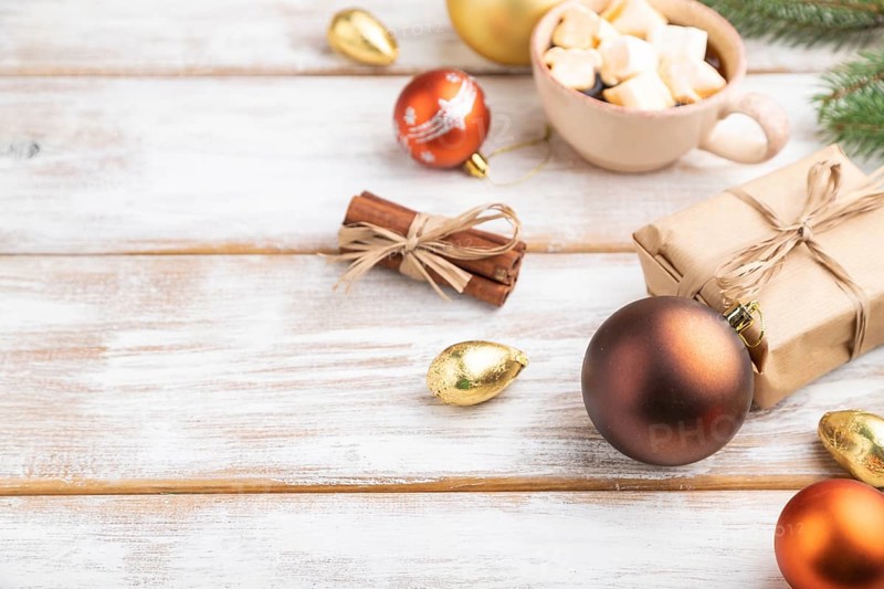 Christmas or New Year composition. Decorations, box, golden balls, cinnamon, fir and spruce branches, cup of coffee, on a white wooden background. Side view, copy space, selective focus