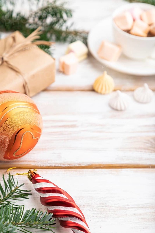 Christmas or New Year composition. Decorations, box, balls, cinnamon, fir and spruce branches, cup of coffee, on a white wooden background. Side view, copy space, selective focus