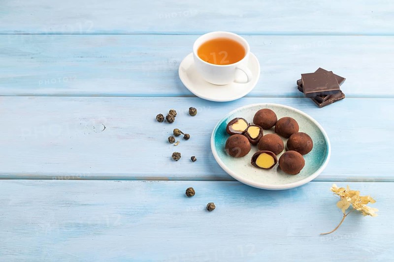 Japanese rice sweet buns chocolate mochi filled with cream and cup of green tea on blue wooden background. side view, copy space