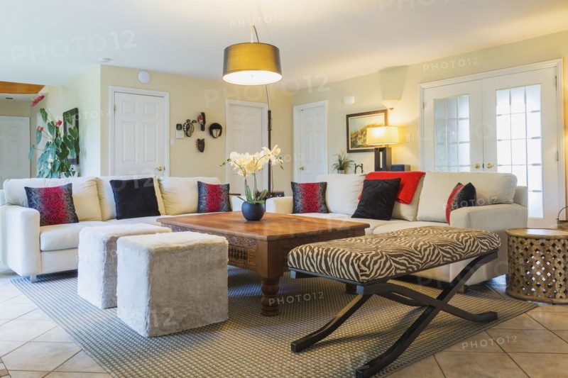 Beige upholstered sofas with colourful cushions, wooden coffee table and zebra motif ottoman in living room inside a luxurious residential home, Quebec, Canada, North America