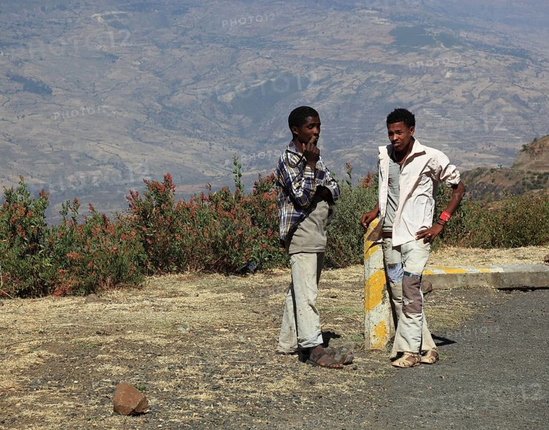 Landscape in the Choke Mountains, two young people waiting for the bus by the road, Ethiopia, Africa