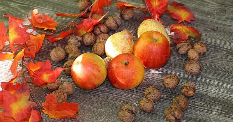 Apples, pears and walnuts on a rustic wooden table as an autumnal motif
