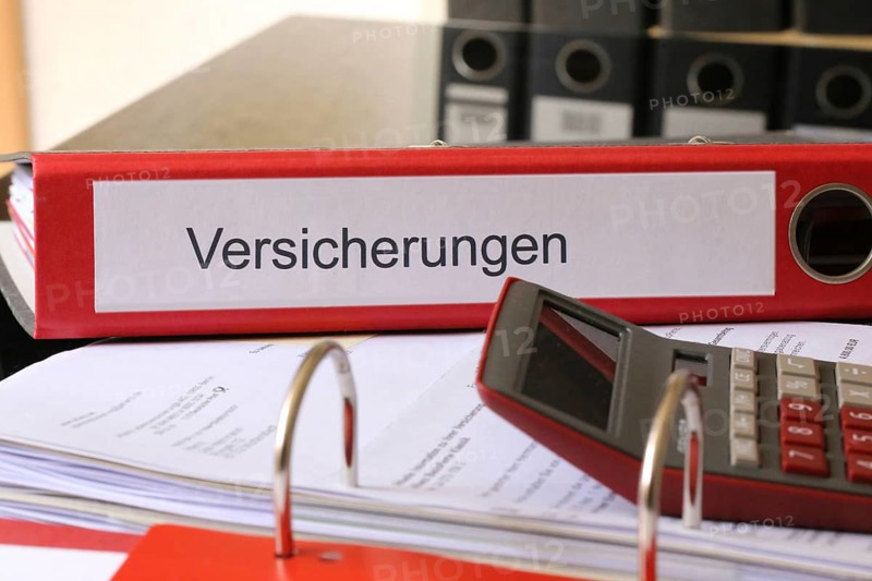 Symbolic image: Folder with insurance policies and calculator on a desk
