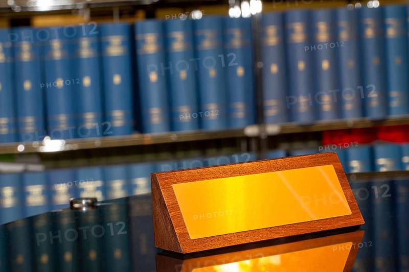 Brass sign with space for text in front of a large bookshelf
