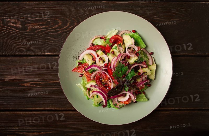 Georgian vegetable salad, tomatoes with cucumbers, red onion, walnut, pomegranate seeds, top view, no people
