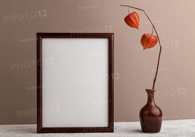 Brown wooden frame mockup with physalis in ceramic vase on beige paper background. Blank, vertical orientation, still life, copy space