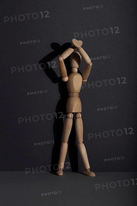 Wooden mannequin stands with raised hands on gray background. protest, attention concept. copy space, hard light